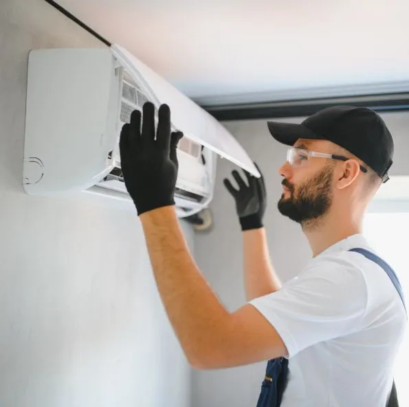 Técnico con lentes de seguridad dando servicio a un minisplit en la pared