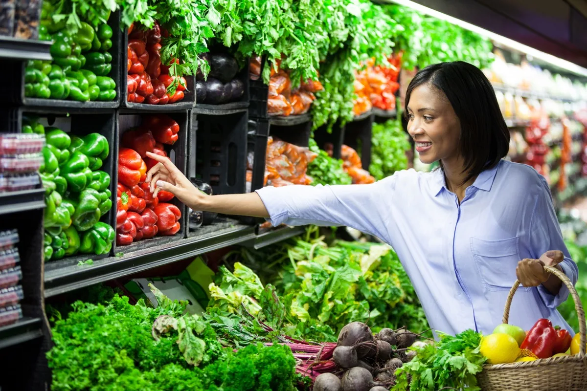 Clienta eligiendo verduras frescas en el pasillo de una tienda