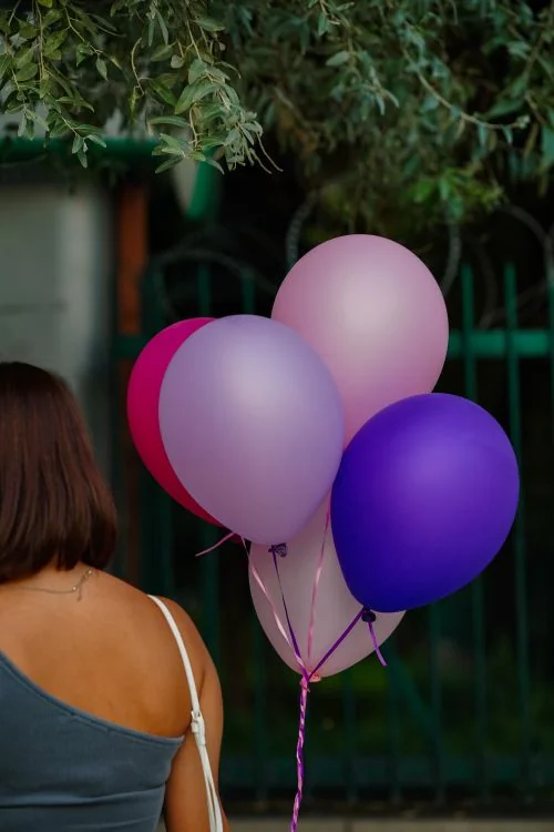 Mujer sosteniendo globos de colores en una fiesta de celebración