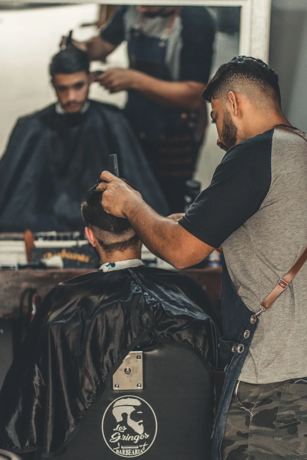 Barbero cortando el pelo a un cliente con máquina en la barbería