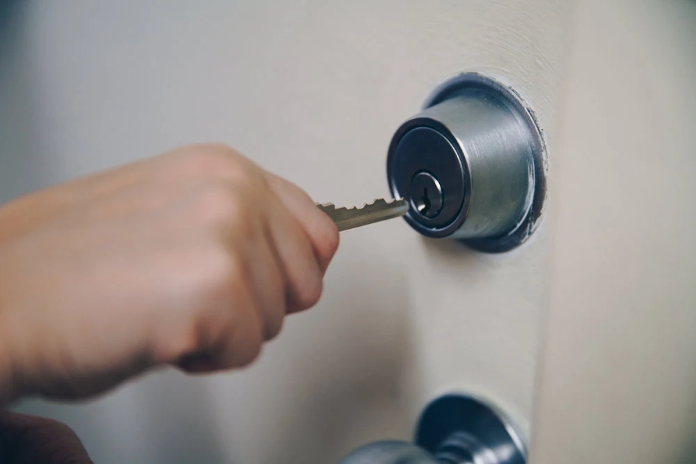 Mano abriendo una puerta con una llave