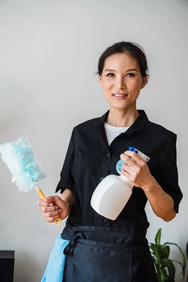 Profesional de limpieza con uniforme y productos de limpieza