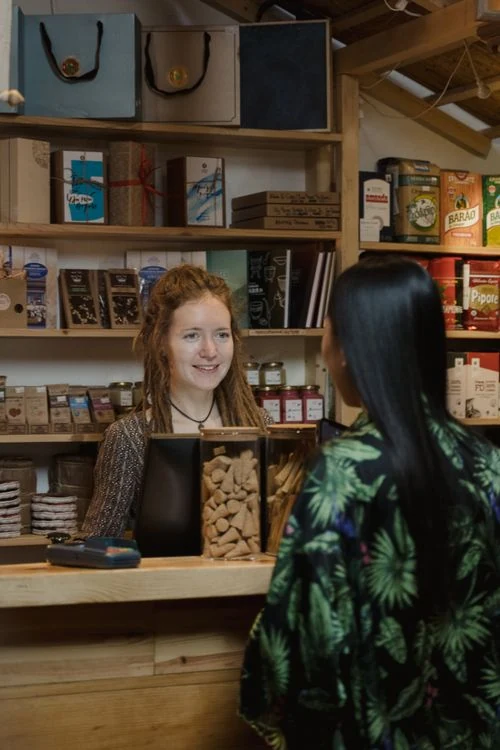 Dueña de tienda atendiendo con amabilidad a una clienta