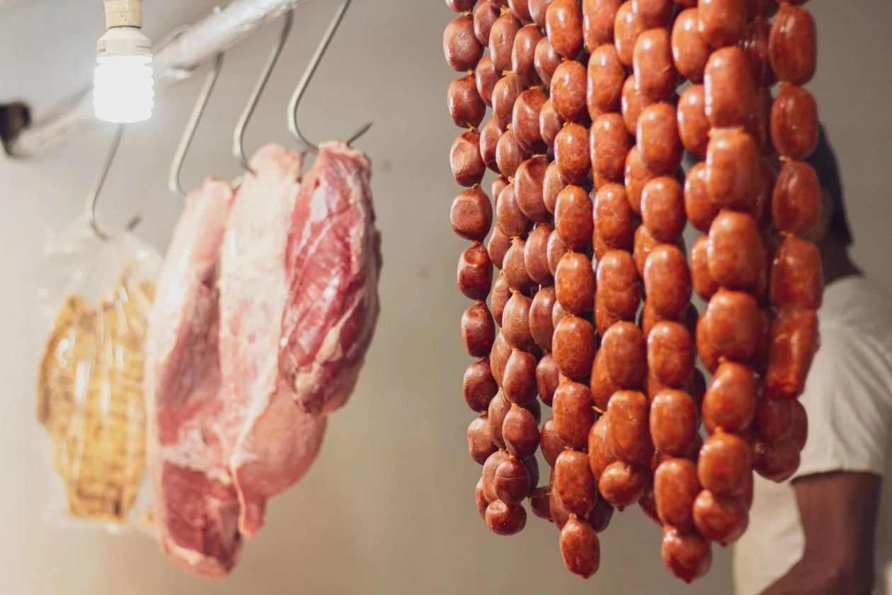 Chorizos y carne de cerdo colgados en la carnicería