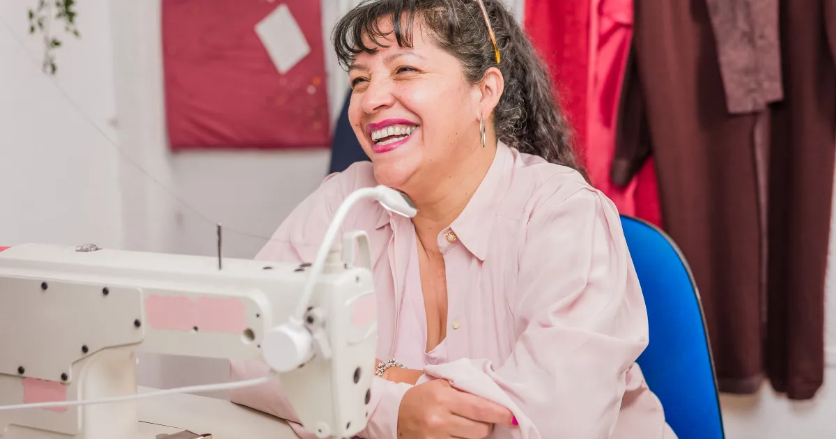 Costurera latina sonriendo en su taller de costura