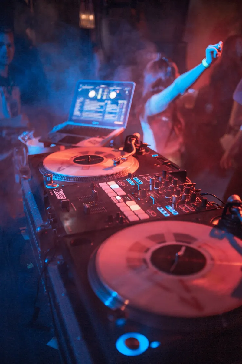 DJ tocando con tornamesas mientras la gente baila en la fiesta