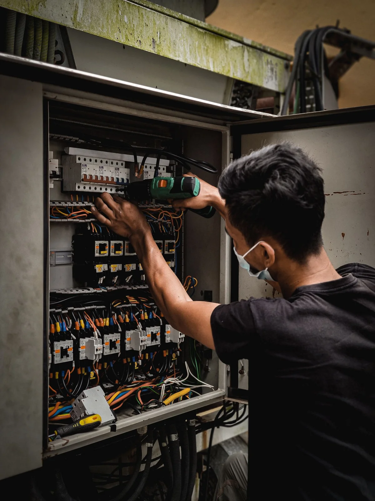 Electricista trabajando en un panel eléctrico con cables