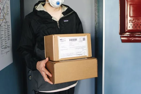 Persona entregando cajas con etiquetas de envío en la puerta