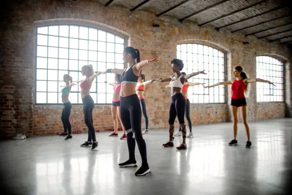 Clase grupal de baile fitness en un salón amplio con ventanales
