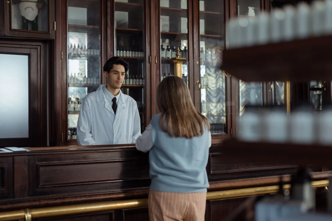 Farmaceutico atendiendo a una clienta en el mostrador