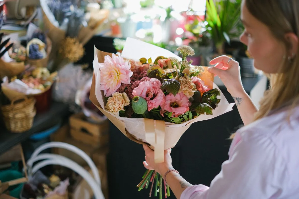 Florista envolviendo un ramo colorido dentro de su tienda