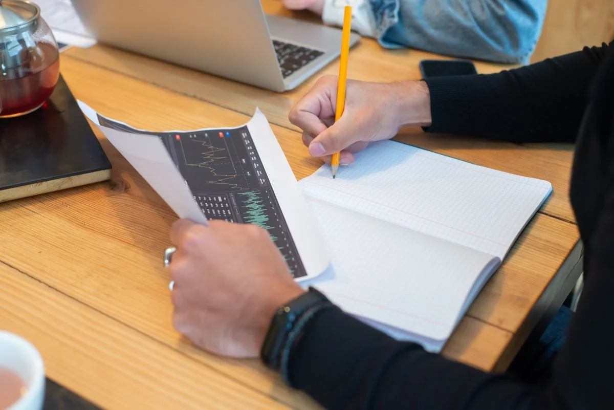 Manos de un emprendedor planeando su negocio con una libreta