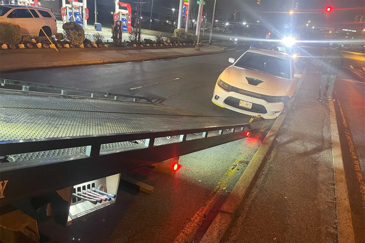 Carro blanco siendo subido a la plataforma de una grúa de noche