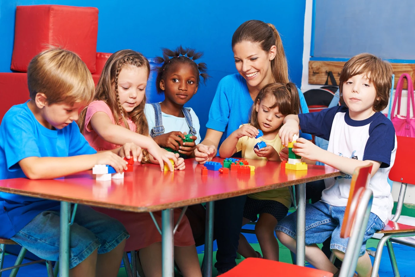 Maestra jugando con niños pequeños en un salón de guardería