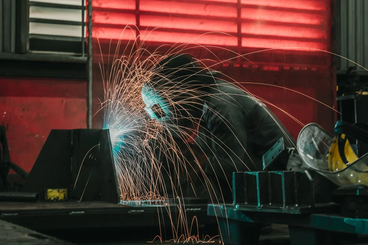 Herrero soldando metal con chispas en su taller