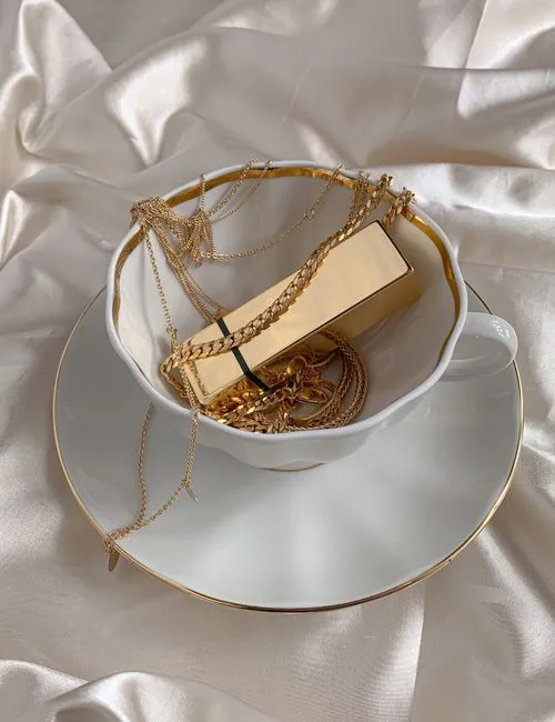 Collares y pulseras de oro en una taza blanca elegante