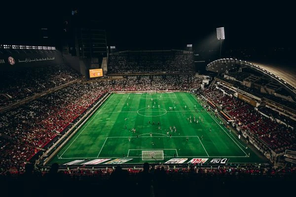 Estadio de fútbol americano de noche con las luces encendidas y tribunas llenas