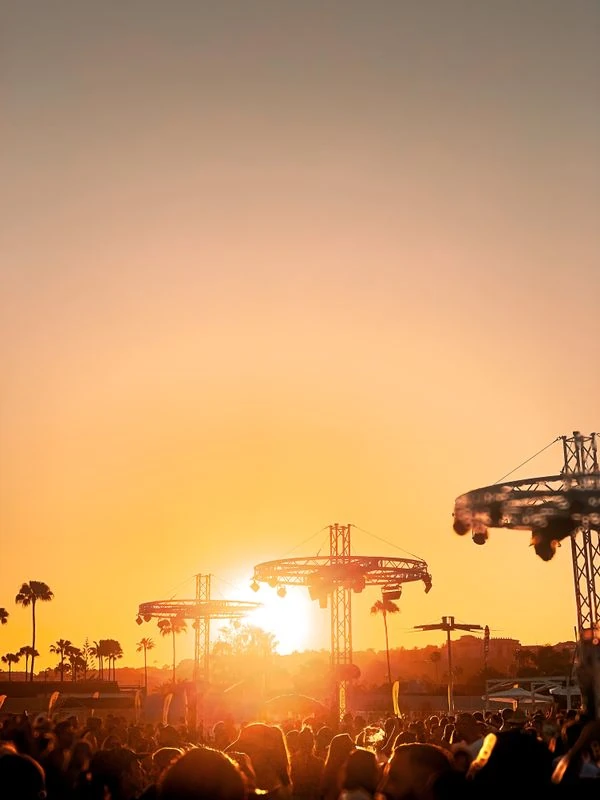 Multitud disfrutando de un festival de música al aire libre al atardecer