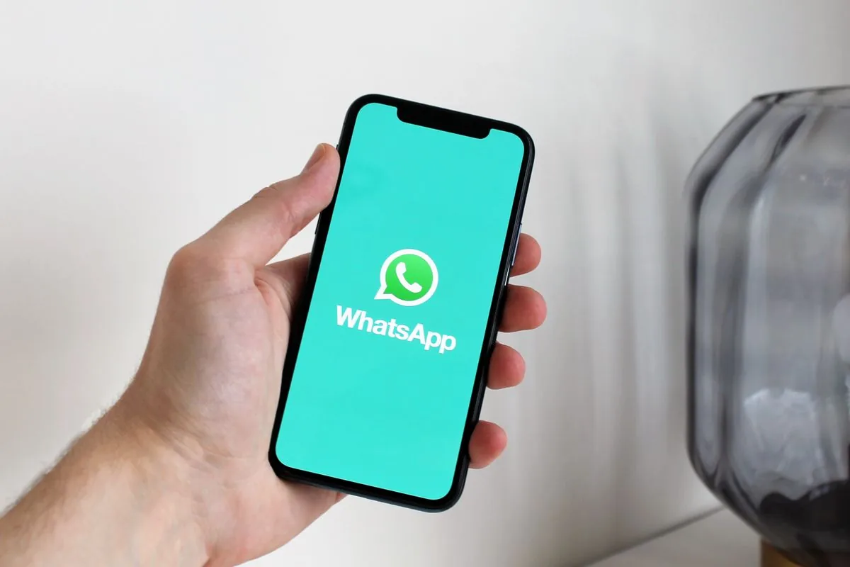 Teléfono en la mano con WhatsApp abierto