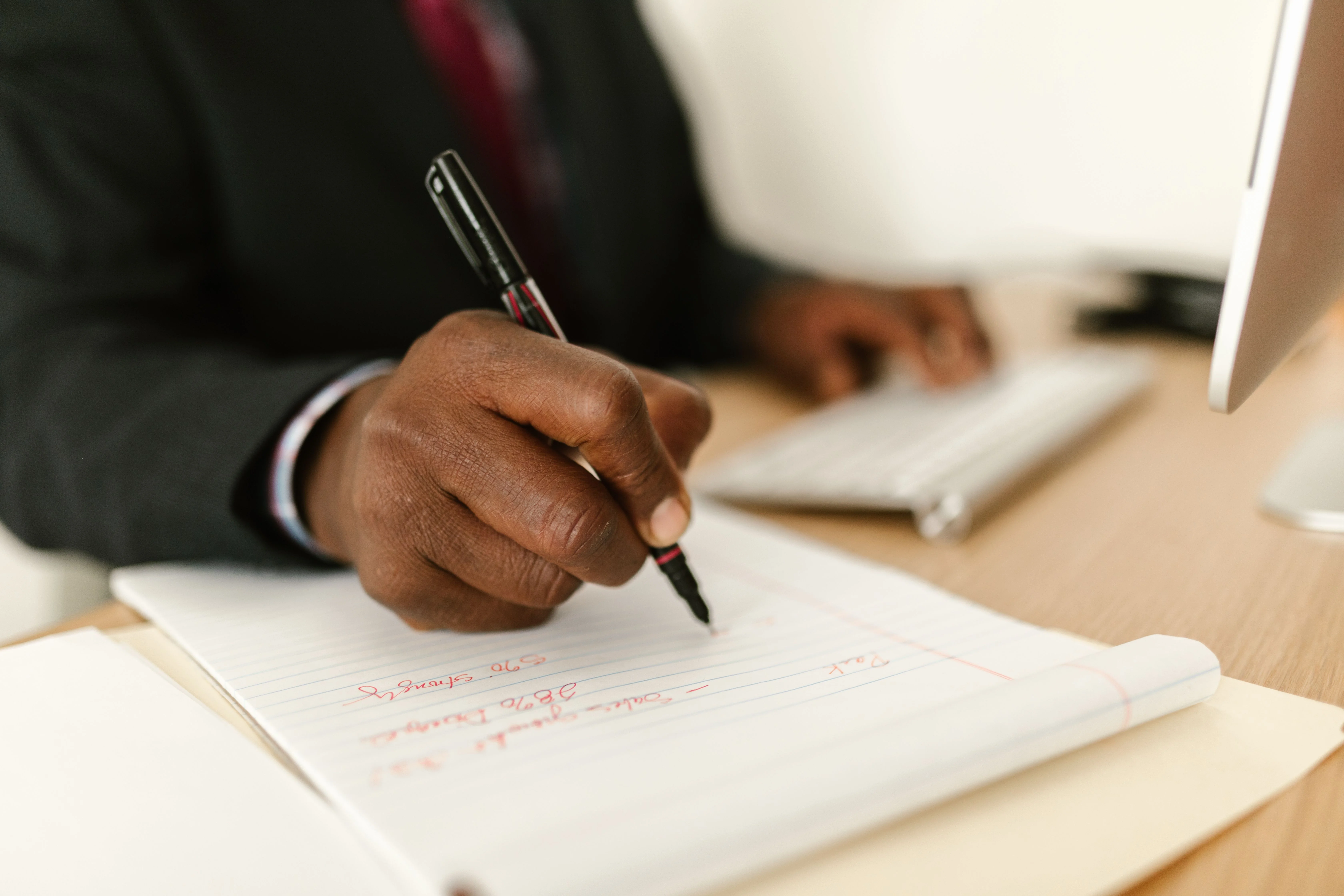 Mano anotando números y notas en una libreta