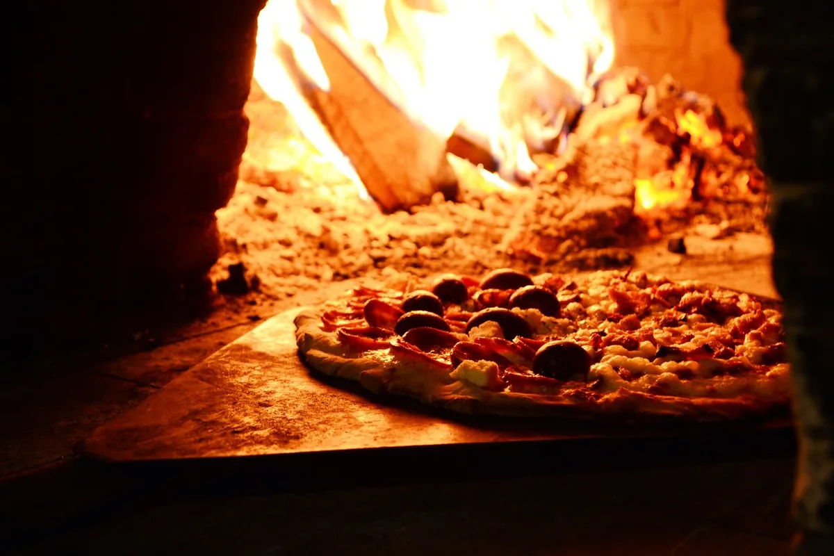 Pizza horneándose en horno de ladrillo de pizzería