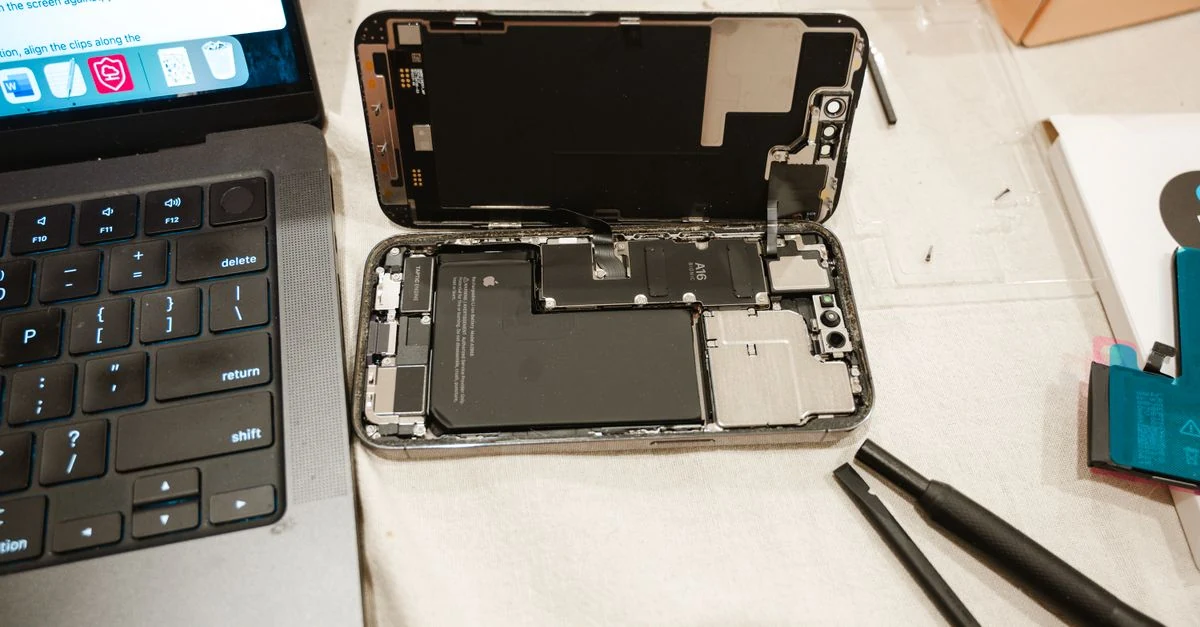 Teléfono abierto durante una reparación junto a una laptop