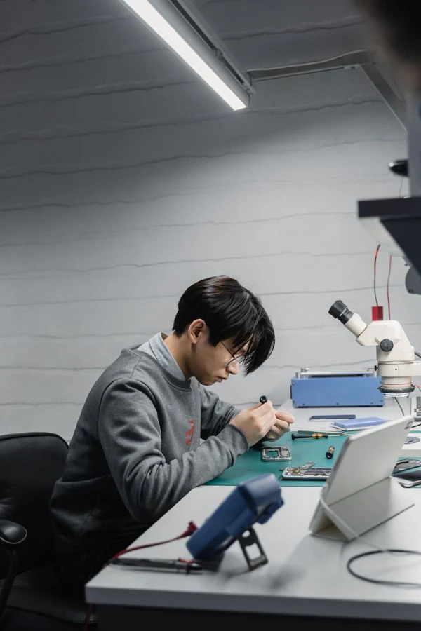 Técnico reparando un celular en su mesa de trabajo