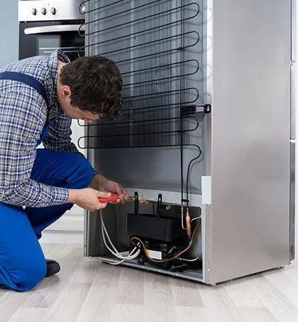 Técnico reparando un refrigerador en una casa