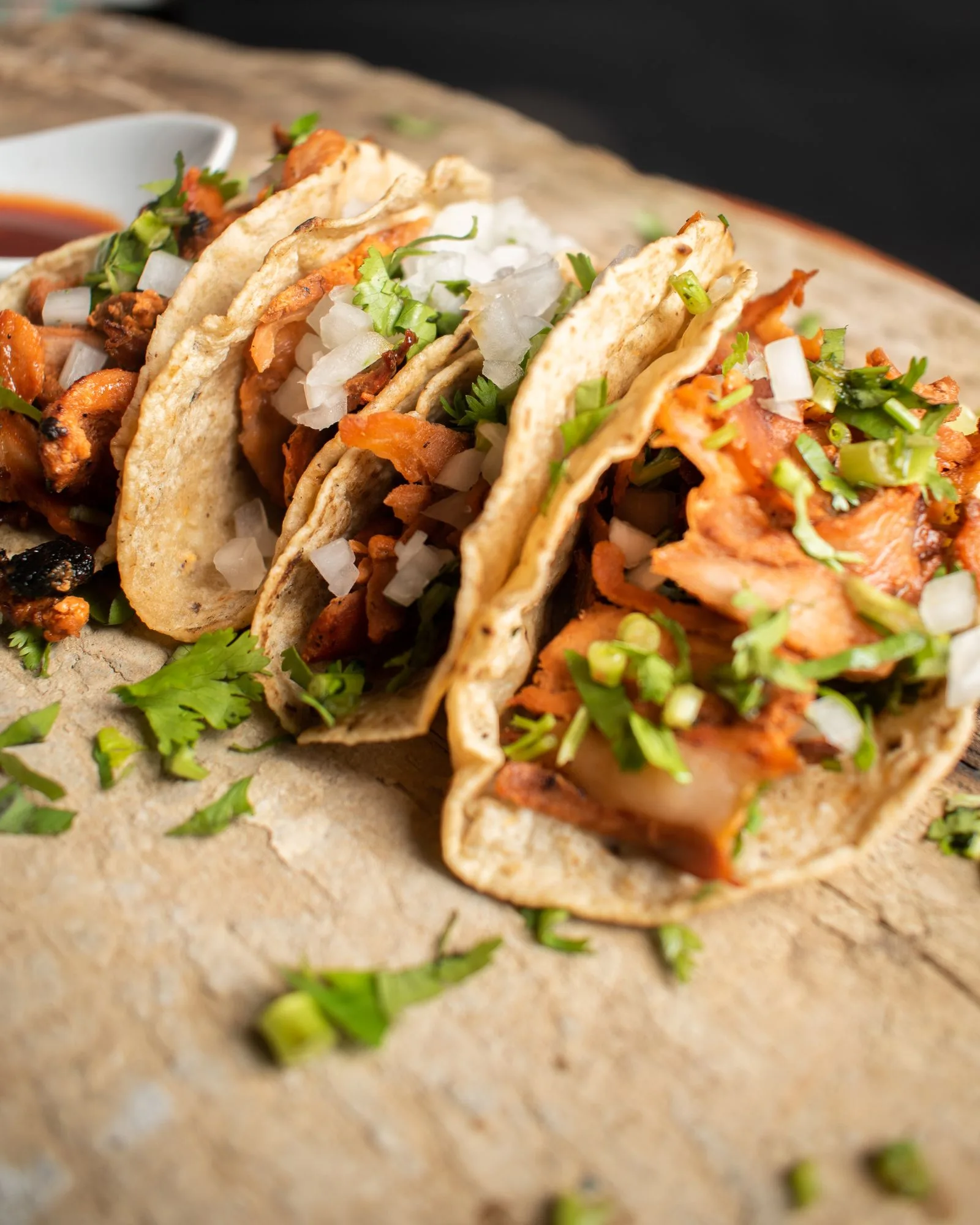 Tacos al pastor servidos con cebolla, piña y salsa, vistos de cerca