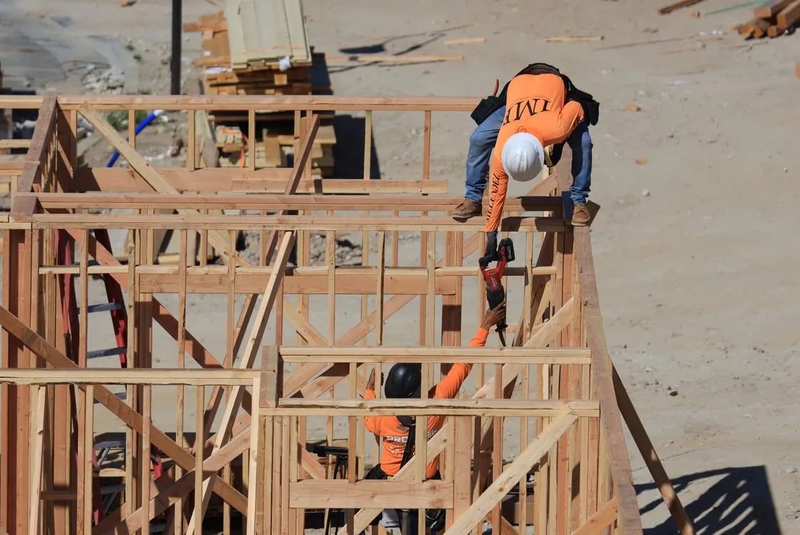 Trabajadores de construcción levantando la estructura de madera de una casa