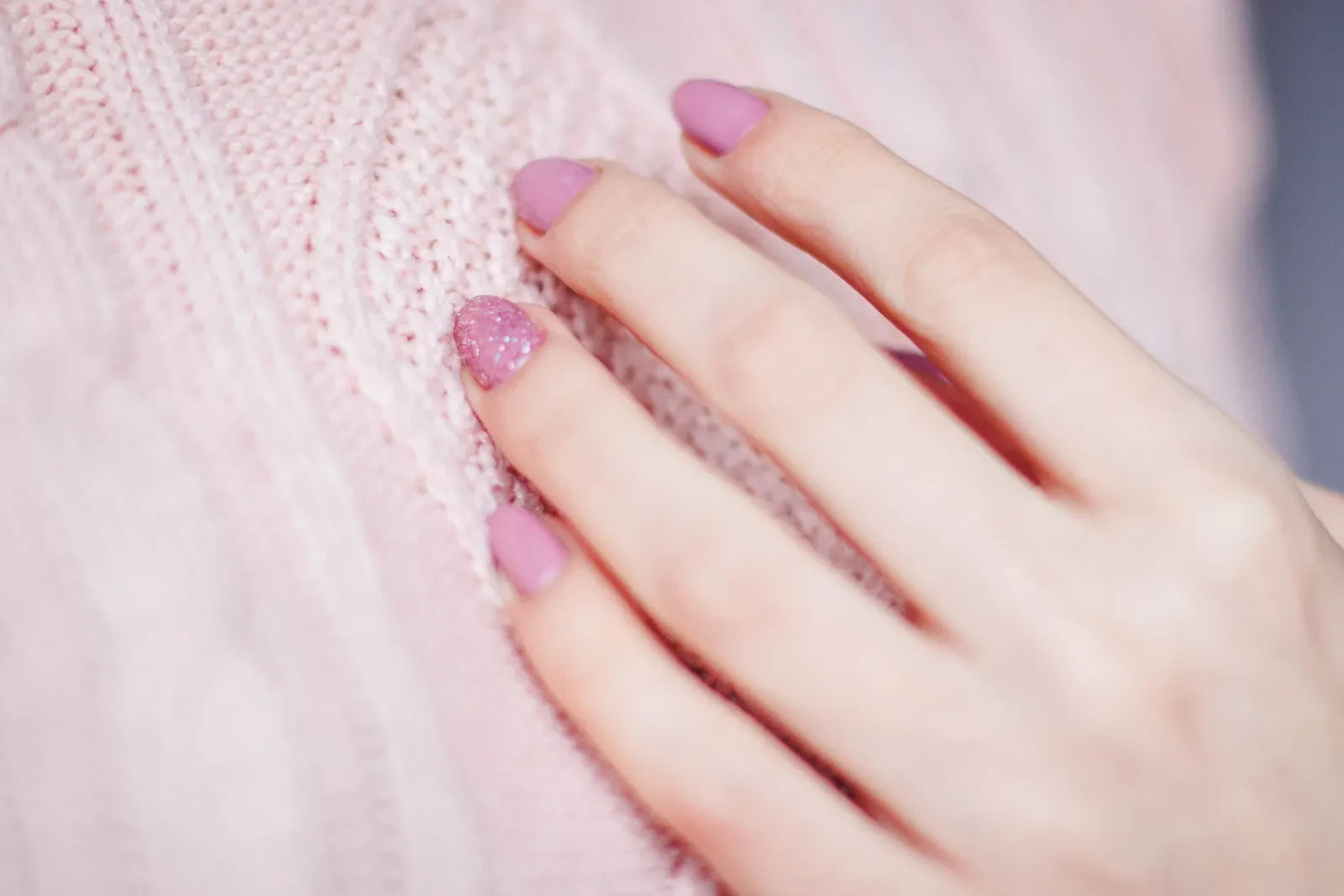 Manos con manicura rosa y diseño de glitter