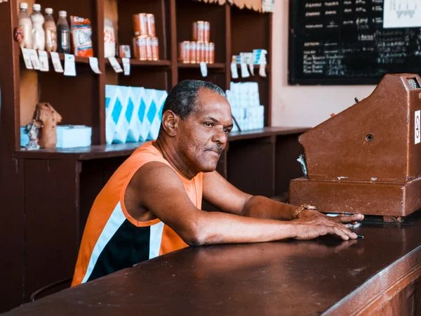 Dueño latino atendiendo en la caja de su tienda