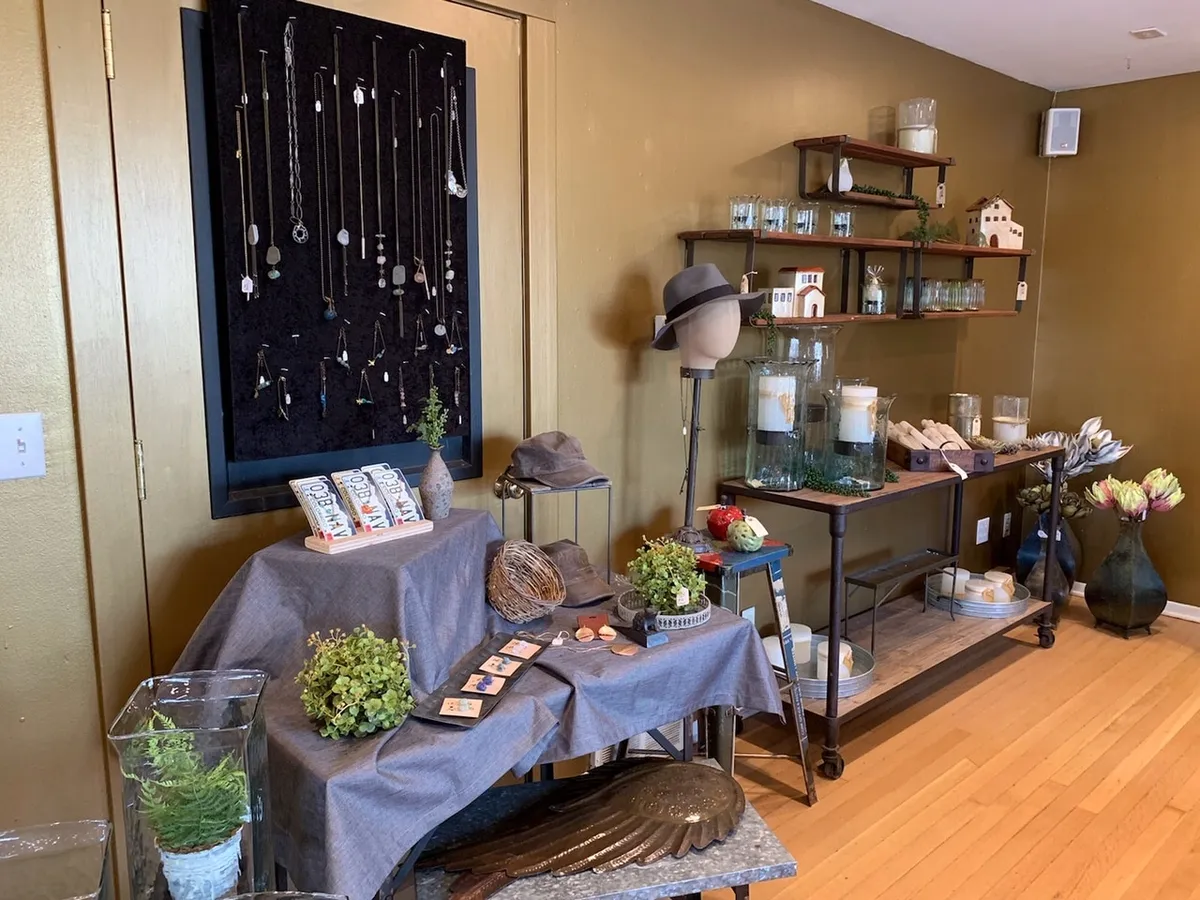 Interior de tienda de regalos con repisas de madera, joyería y velas