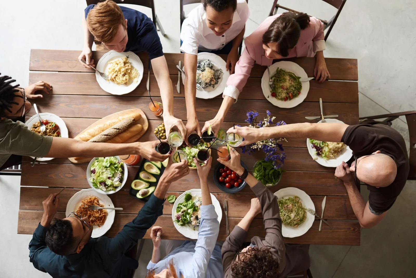Amigos brindando alrededor de una mesa de restaurante llena de comida