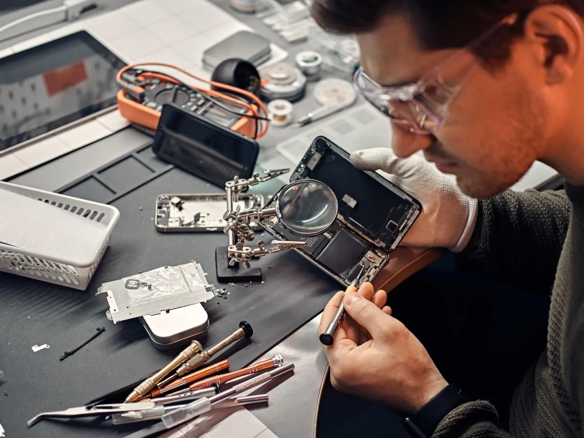 Técnico reparando un celular abierto en banco de trabajo