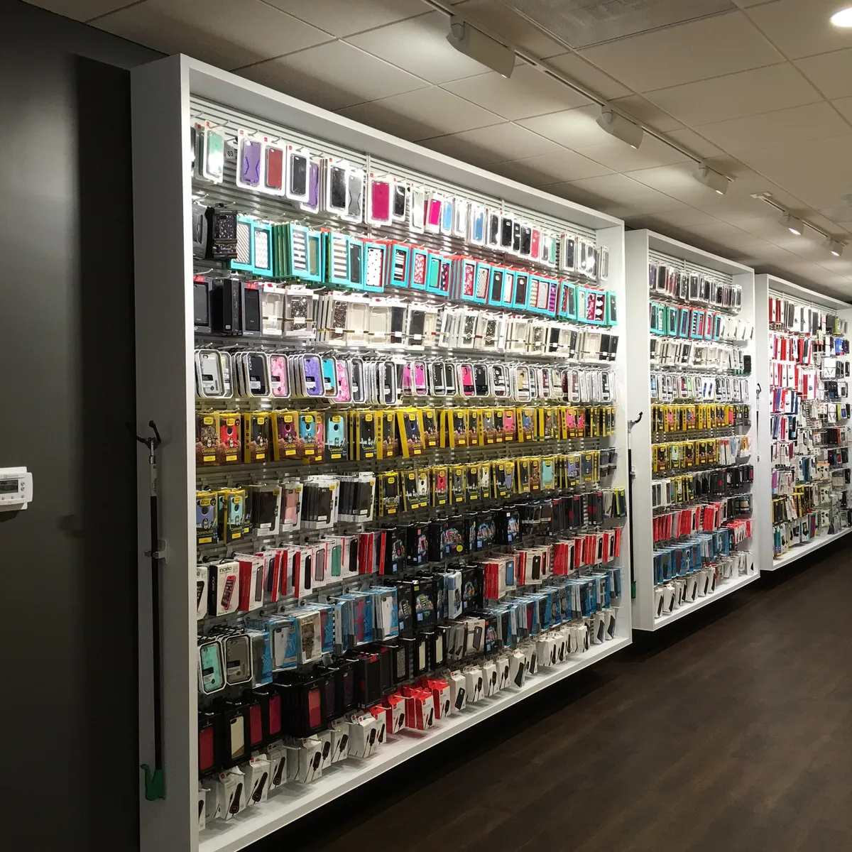 Pared de exhibición de fundas para celular en tienda, organizadas por color