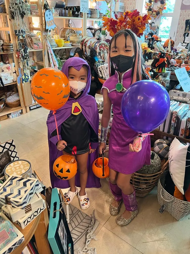 Dos niños con disfraces de Halloween y cubetas de calabaza dentro de una tienda