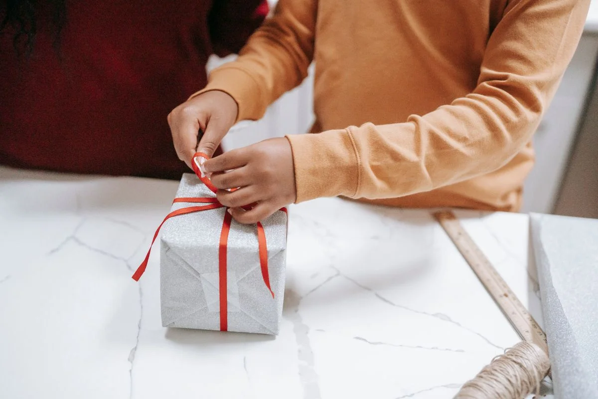 Manos envolviendo un regalo con moño para las fiestas