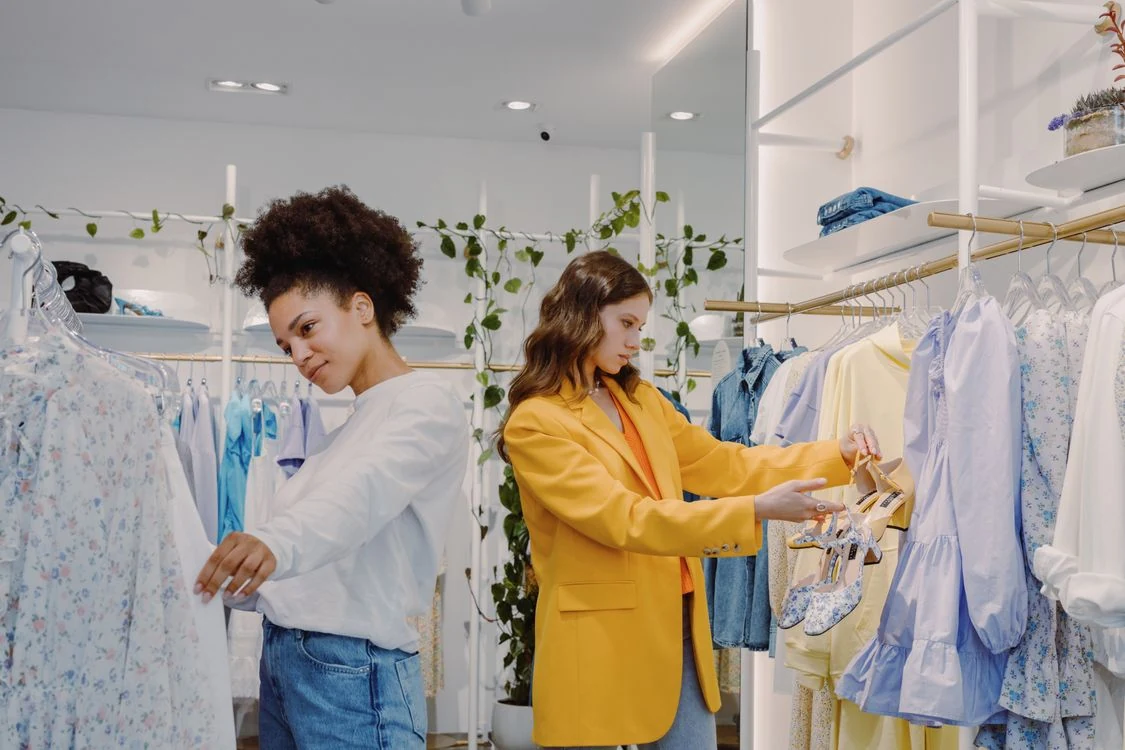 Dos clientas comprando ropa en una tienda iluminada