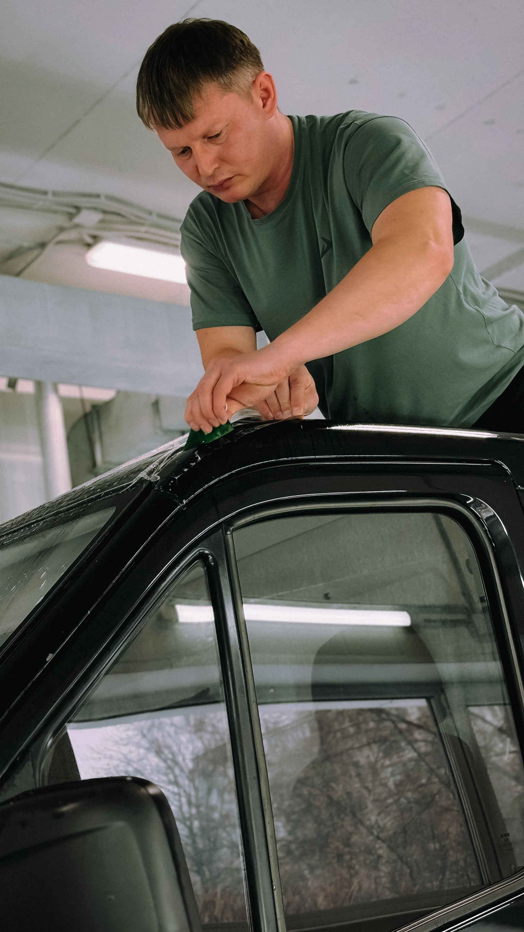 Trabajador instalando película para vidrios en un carro