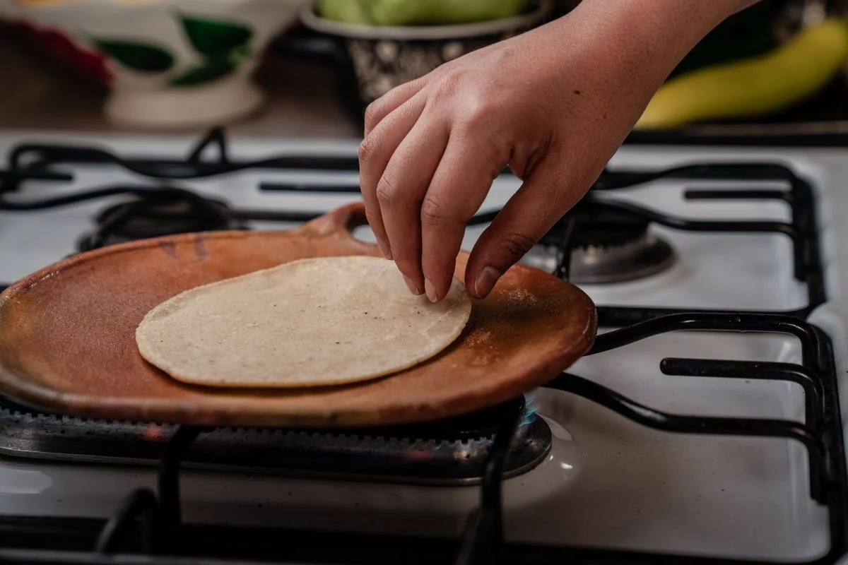 Manos extendiendo tortillas calientes sobre el comal en una tortillería latina de Memphis