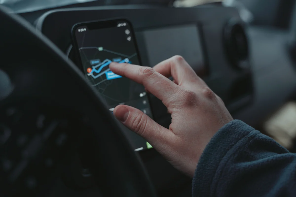 Persona usando el teléfono con el mapa en su carro